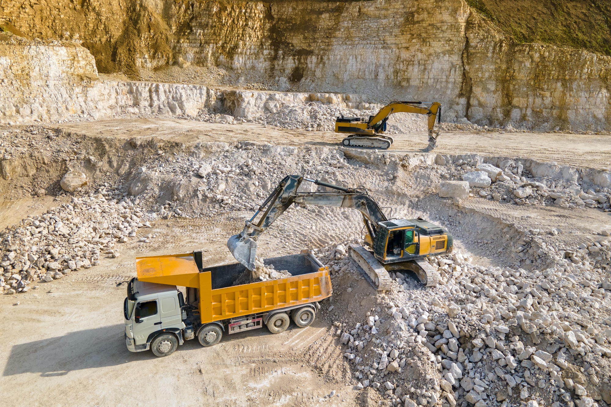 Open pit mining of construction sand stone materials with excavators and dump trucks
